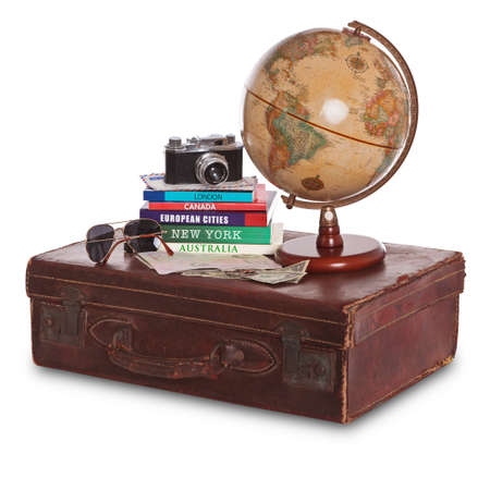 Still-life photo of an old brown leather suitcase with camera, travel guides, world globe, sunglasses, stamped passport and money. Isolated on a white background with clipping path.の写真素材