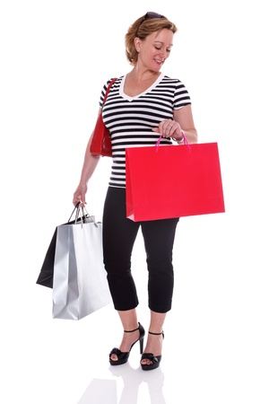 A well dressed mature woman holding shopping bags and checking the time on her watch, isolated on a white background の写真素材