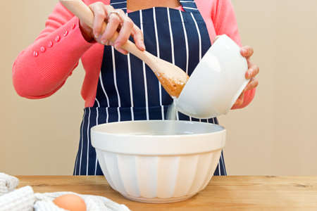 A woman at home in her kitchen making a cakeの写真素材
