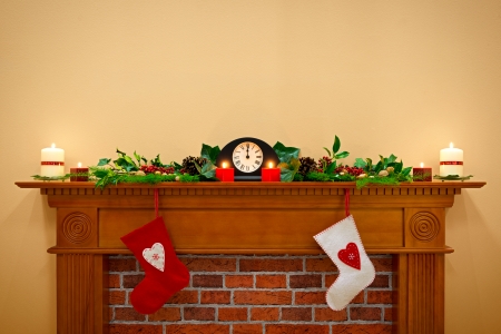 Christmas stockings hanging over the fireplace at midnight on Christmas Eve, the mantlepiece is decorated with festive holly and ivy garland plus candles. Plenty of copy space to add your own message.の写真素材