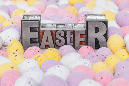 The word Easter in old metal letterpress surrounded by candy covered mini chocolate eggs.の写真素材