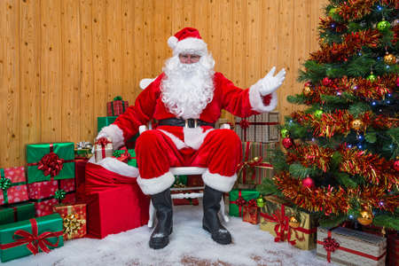 Santa Claus getting a gift wrapped present out of his sack as he welcomes you into his grotto.の写真素材