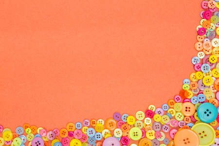 Lots of colourful buttons on an orange textured paper background with blank copy space.