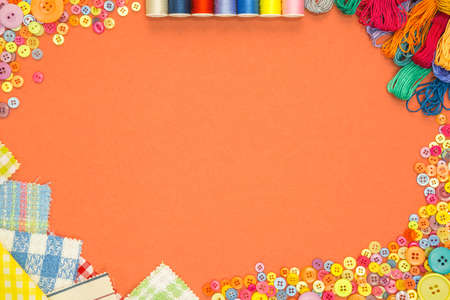 Arts and Crafts background with material and buttons on an orange textured paper background with blank copy space.の写真素材