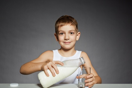 Boy pouring milk into glassの写真素材