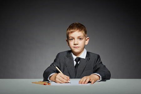 Boy in suit writingの写真素材