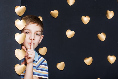 Boy peeking on golden hearts dark backgroundの写真素材