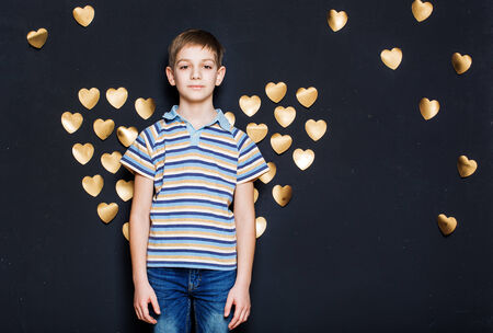 Boy with  golden heart wings on dark background
