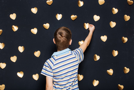 Boy attaching hearts on dark backgroundの写真素材