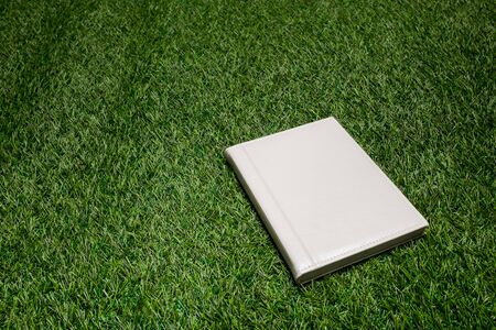 White leather book lying on the grassの写真素材