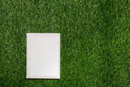 White leather empty book lying on the grassの写真素材