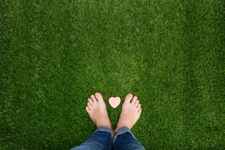 Feet standing on grass with small heartの写真素材