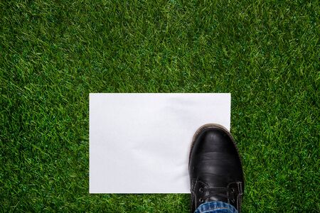 Boot standig on white sheet of paper on the grassの写真素材