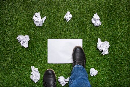 Boots on sheet of paper with cramled sheets on the grassの写真素材
