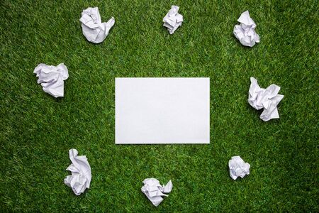 White sheets of paper with cramled sheets on the grassの写真素材