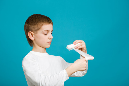 Unhappy boy taping up bandage on his handの写真素材