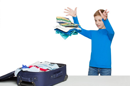 Boy throwing many clothes to luggage bagの写真素材