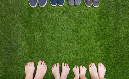 Family legs standing with shoes on green grassの写真素材