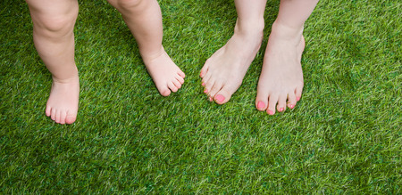 Little baby and mother legs standing  on grass