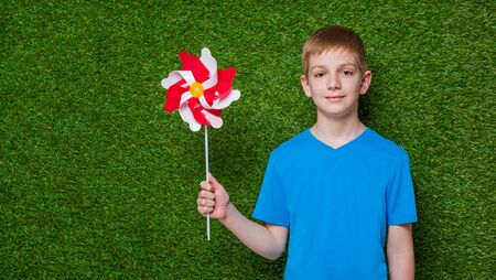 Portrait of a boy holding pinwheel over grassの写真素材