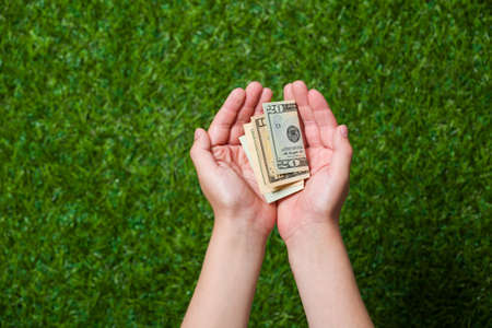 Human hands holding money over green grassの写真素材