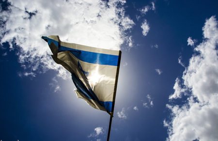 Old Israeli flag waving at sunny day on blue sky backgroundの写真素材