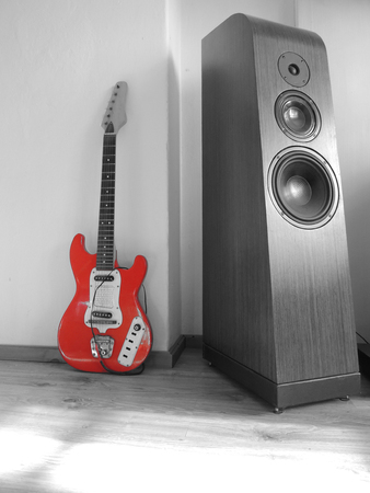 Piece of an old and used electric guitar standing near big loudspeakerの写真素材