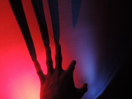 Hand throwing shadow on the colorful backgroundの写真素材