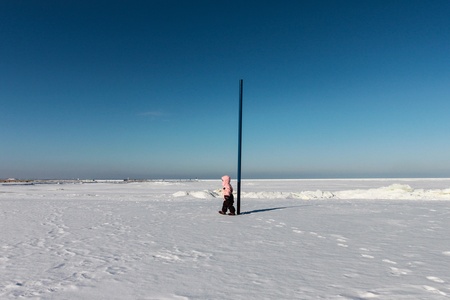 Child girl walks on snow near the seaの写真素材