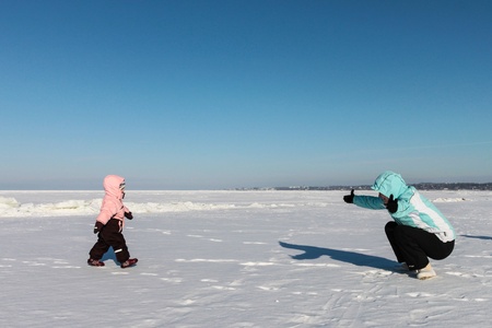 Mother and baby girl play on snowの写真素材