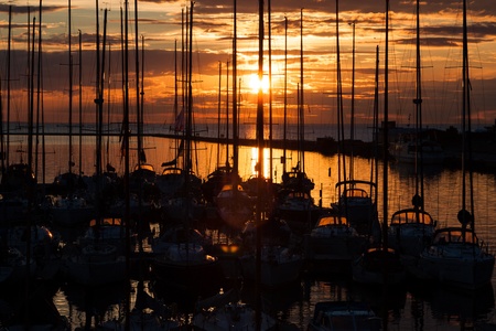 Sailboats in sea harbor with sunset and cloudsの写真素材