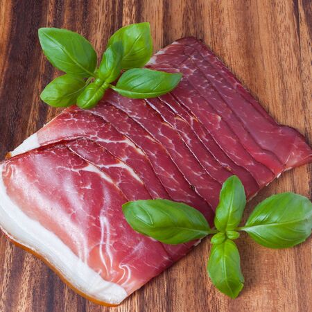 Pressed ham meat on wooden board with basil leafsの写真素材