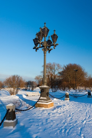 Antique frosty lamppost and beautiful snow covered branches against the azure skyの写真素材