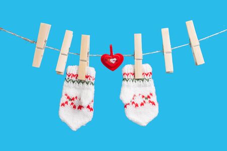 Two mittens and heart on clothesline with clothespins, blue backgroundの写真素材