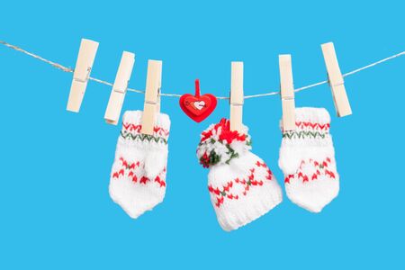 Two gloves, hat and heart on clothesline with clothespins, blue backgroundの写真素材
