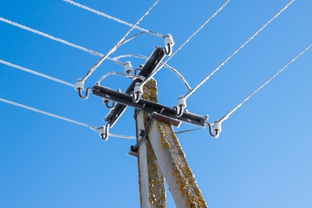 Power lines dripping with icicles against a clear blue skyの写真素材