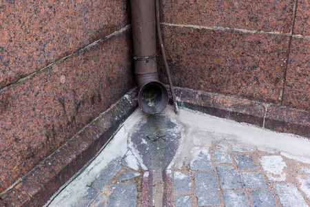the old gutter in the old town with red granite wallの写真素材