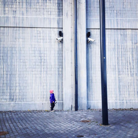 Child near wall with security camerasの素材