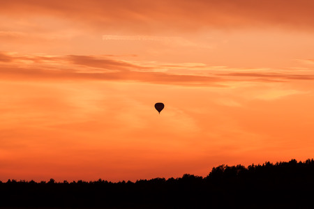 Hot air balloon flying at orange sunset skyの写真素材