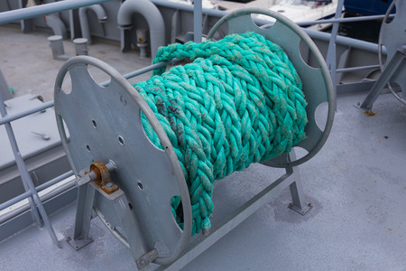 Close-up of a mooring rope with a knotted end tied around a cleat on a wooden pier/ Nautical mooring...