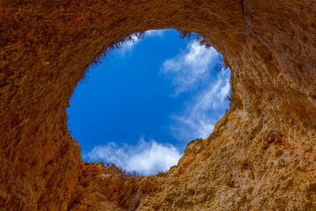 Hole of a big cave in the stones of the beach, Algarve Portugalの写真素材
