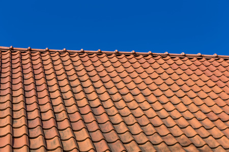Red roof tile pattern over blue skyの写真素材