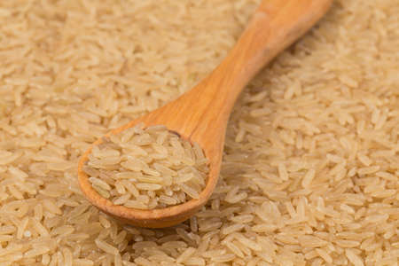 Uncooked Brown rice background close up image with wooden spoonの写真素材