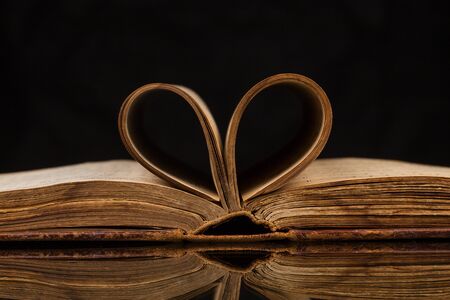 Opened old book with reflected in black surfaceの写真素材