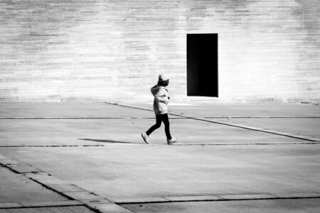 Child looking  at dark black and white doorの写真素材