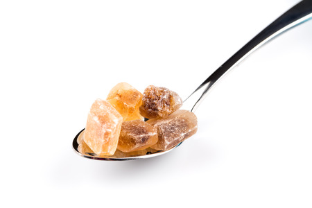 brown caramelized sugar in a wooden spoon on a white backgroundの写真素材