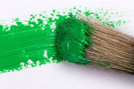 green stroke of the paint brush on white paper