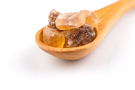brown caramelized sugar in a wooden spoon on a white backgroundの写真素材