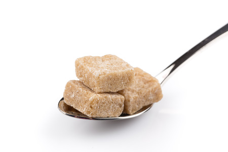 Cubes of brown sugar on a metal spoonの写真素材