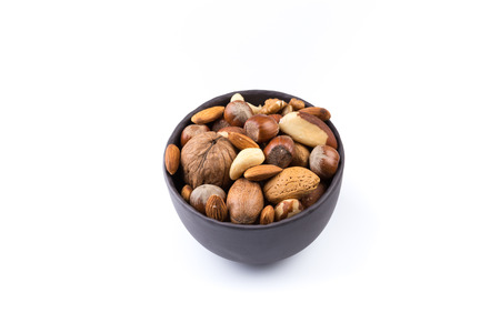 Large diversity of healthy nuts in a dark stone bowl - isolatedの写真素材